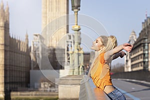 A happy tourist woman stands on the Westminster Bridge in London