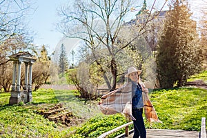 Happy tourist woman walks by Olesko Castle in spring park admiring view of architecture. Sightseeing in Western Ukraine