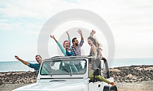 Happy tourists friends doing excursion on desert beach in convertible 4x4 car - Young people having fun traveling together -