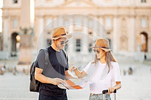 Happy tourists looking at a map and choose a hotel. Couple of tourists on vacation in Rome, Italy. Satisfied tourists