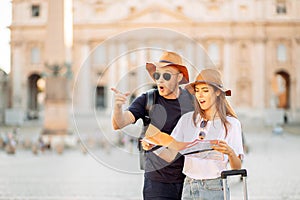 Happy tourists looking at a map and choose a hotel. Couple of tourists on vacation in Rome, Italy. Satisfied tourists