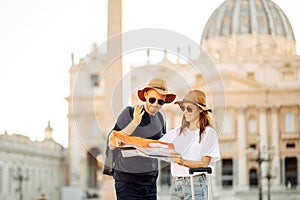 Happy tourists looking at a map and choose a hotel. Couple of tourists on vacation in Rome, Italy. Satisfied tourists