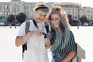 Happy tourists looking at photos on camera