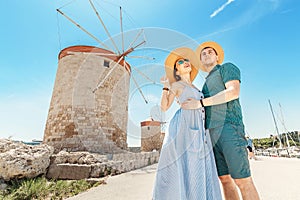 Happy tourists travel in Rhodes town in front of the famous Windmills. Greece vacation concept