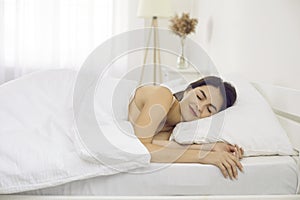 Happy tranquil beautiful woman napping lying on comfortable bedding in bedroom at home alone.
