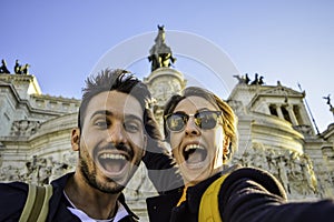 Happy travel couple taking selfie with the smartphone in famous landmark in la Piazza Venezia, Rome, Italy