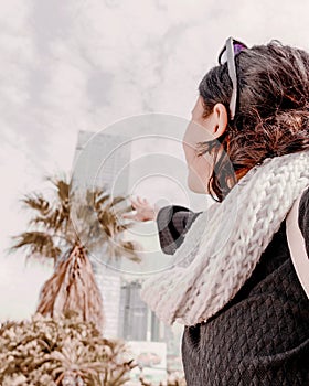 Happy travel girl reaches out to the office building and palm tree.