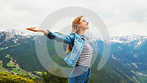 Happy travel woman enjoys fresh air mountains raises hands up