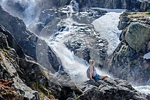 A happy traveler admires a beautiful waterfall on a sunny day.