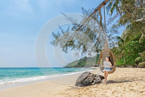 Happy traveler Asian woman relaxing on luxury swing and looking beautiful nature landscape beach. summer holiday vacation travel