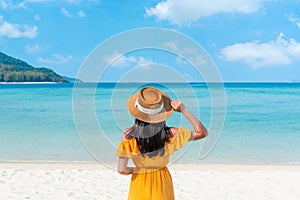Happy traveler Asian woman on yellow dress relax on the tropical sandy beach. Summer, vacation concept. Copy space