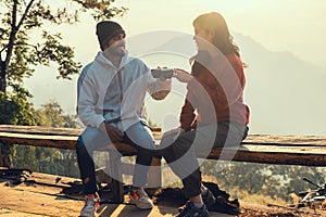 Happy traveler couple resting on mountains in sunrise