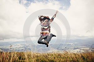 Happy traveler hipster girl in hat, jumping with backpack and sm