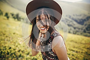 Happy traveler hipster girl in hat, walking in sunny mountains.