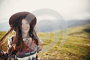 Happy traveler hipster girl with windy hair smiling, standing o