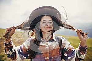 Happy traveler hipster girl with windy hair smiling, standing o