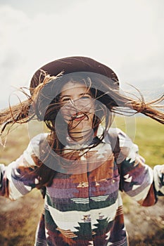 Happy traveler hipster girl with windy hair smiling, standing o