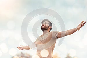 Happy Traveler male embracing life and enjoying freedom with open arms over sky and bokeh effect. Carefree smiling Bearded man