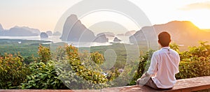 Happy traveler man enjoy Phang Nga bay view point, alone Tourist sitting and relaxing at Samet Nang She, near Phuket in Southern