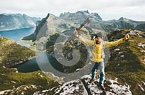 Happy traveler man success raised hands standing on mountain top