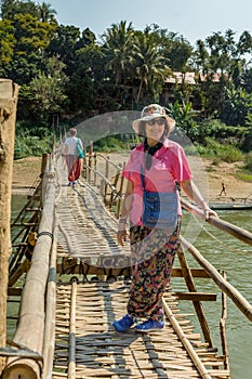 Happy traveler posing on bamboo bridge over the Nam Kahn River in Luang Prabang, Laos