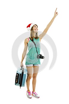 Happy traveler in santa hat with camera and suitcase going on vacation, pointing up