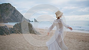 Happy traveler spinning beach on cloudy summer day. Carefree woman enjoying