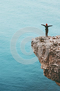 Happy traveler standing on cliff above sea hands raised Travel Lifestyle success motivation concept