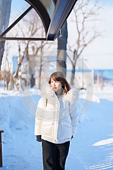 happy Traveler with Sweater and backpack walking on snow covered road in frosty weather, woman tourist sightseeing in Sapporo city