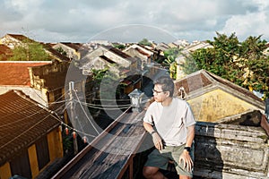 Happy traveler traveling at Hoi An ancient town in Vietnam, man sightseeing view at rooftop. landmark and popular for tourist