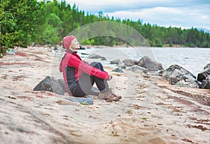 Happy traveler trekking woman sitting on the coast of sea