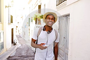 Happy traveler walking in town with mobile phone and bag