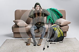 happy traveler wearing hat and hiking boots on sofa