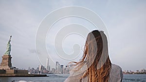 Happy traveler woman with hair blowing in the wind enjoying New York skyline at Statue of Liberty on a boat slow motion.