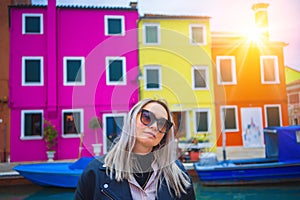 Happy traveler woman having fun near colorful houses on Burano island in Venetian lagoon. Travel and vacation in Italy