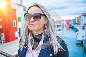 Happy traveler woman having fun near colorful houses on Burano island in Venetian lagoon. Travel and vacation in Italy