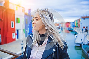 Happy traveler woman having fun near colorful houses on Burano island in Venetian lagoon. Travel and vacation in Italy