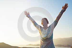 Happy traveler, woman with open arms stands on the rock