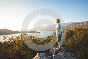 Happy traveler, woman with open arms stands on the rock