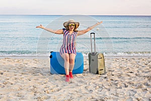 Happy traveler woman with suitcase on the beach. Concept of travel, journey, trip