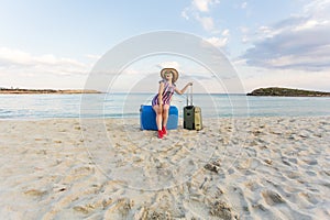 Happy traveler woman with suitcase on the beach. Concept of travel, journey, trip