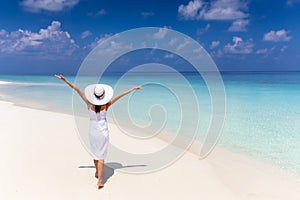Happy traveler woman in white dress enjoys her tropical beach vacation