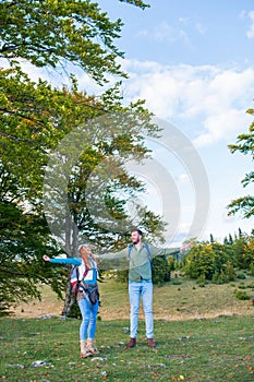 Happy travelers couple conquered top of mountain, raises hands up