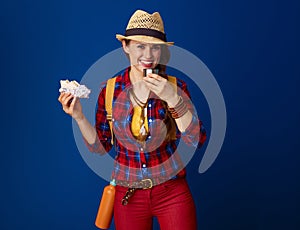 Happy traveller woman against blue background having meal break