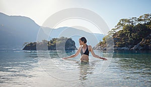 Happy traveller woman in black swimsuit enjoys her tropical beach vacation