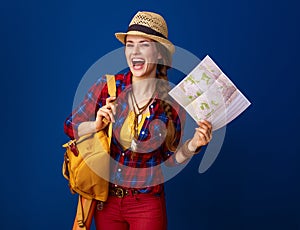 Happy traveller woman isolated on blue background with map