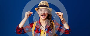 Happy traveller woman isolated on blue holding headphones