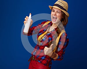 Happy traveller woman showing thumbs up showing bottle of spray