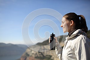 Happy trekker holding water bottle looking away