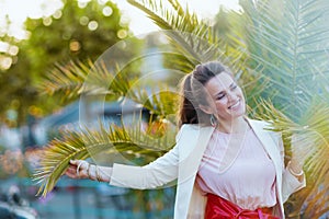 happy trendy 40 years old woman in dress and jacket in city